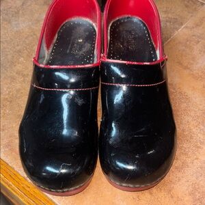 pair of Sanita Professional clogs in black patent leather with red trim